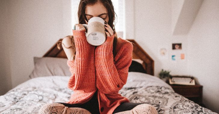 woman in red knit sweater holding mug