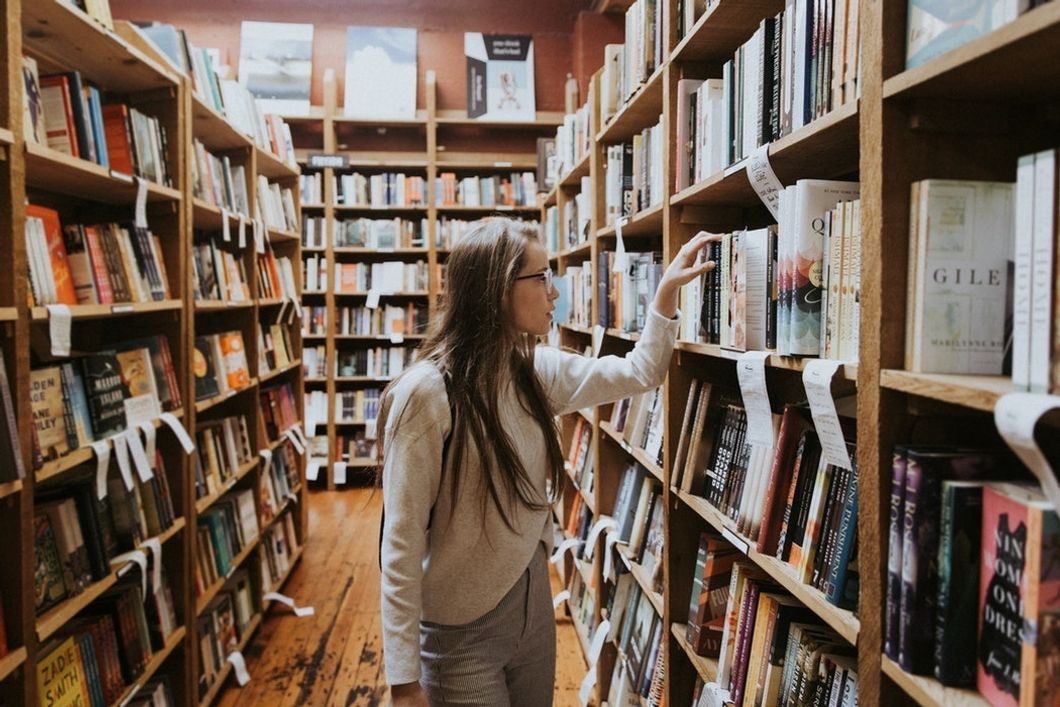 woman looking at books on shelf in bookstore