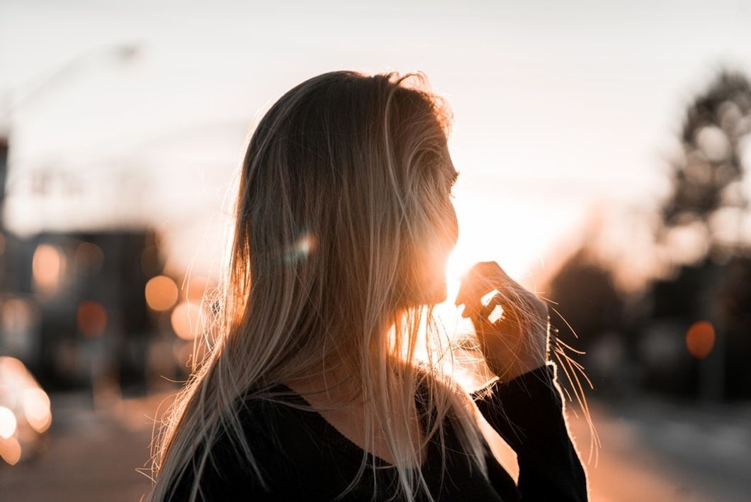 woman outside looking at sunset playing with hair
