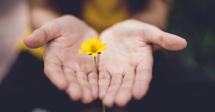 woman palms out delivering a flower