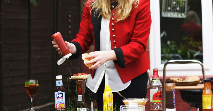 woman putting red sauce on hamburger