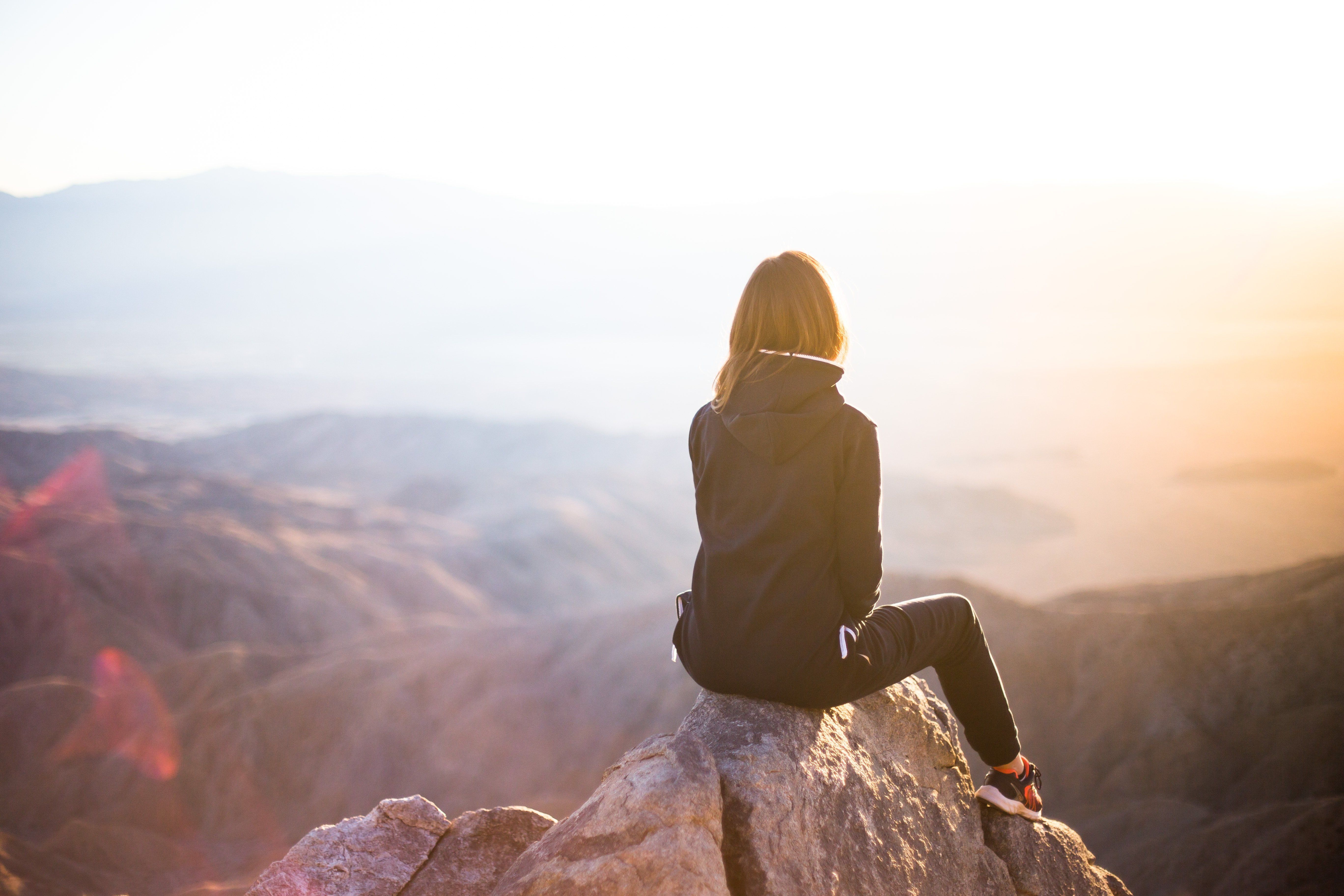 woman sits atop mountain pondering how to have glow up