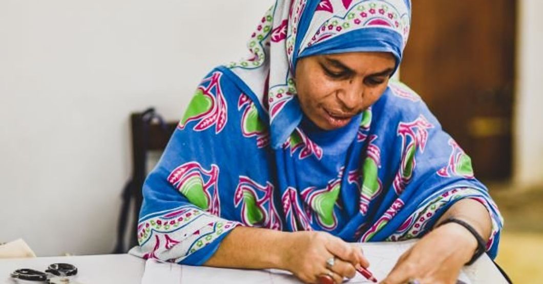 Woman sitting and drawing patterns for cusions