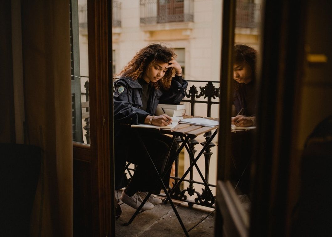 woman sitting at table outside working on homework