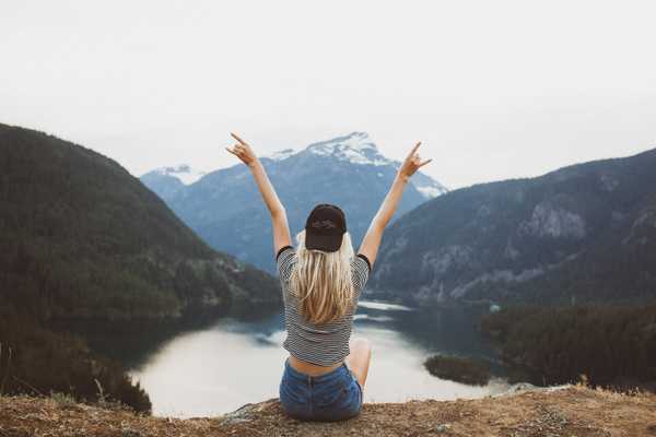 Woman sitting on a cliff with arms in the air