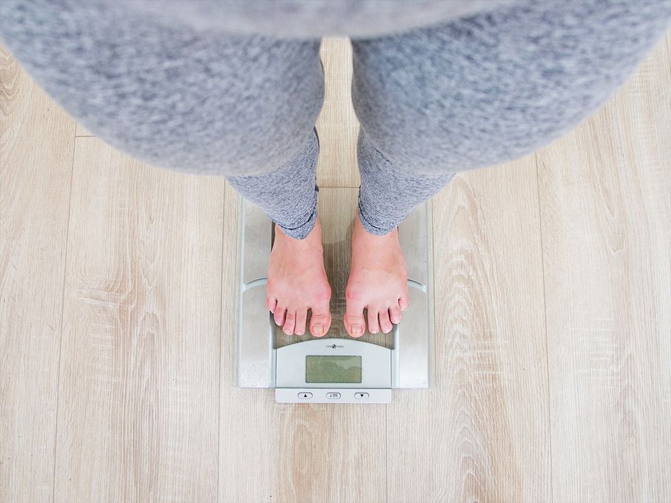 woman stands on scale to weigh herself after working out regularly