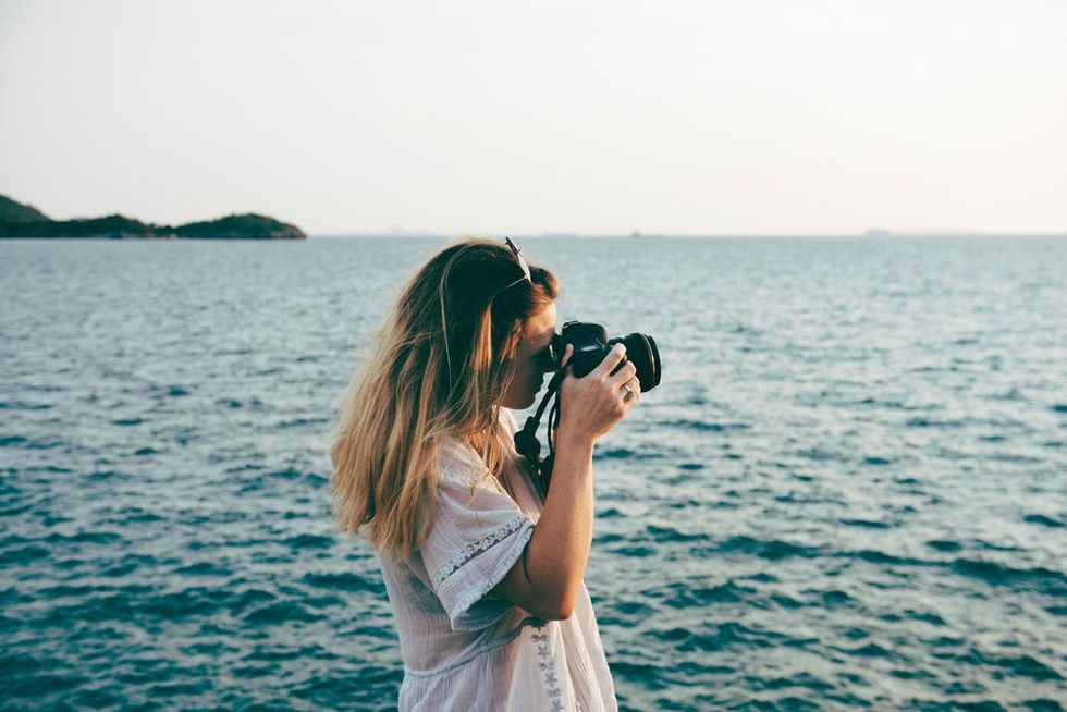 woman takes a photograph by the water