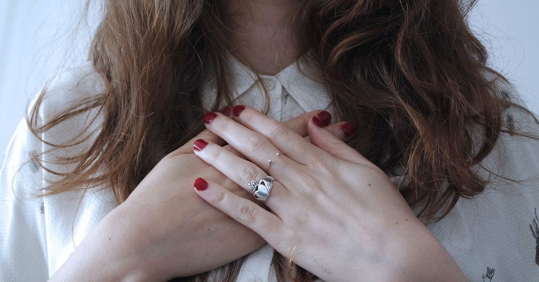 woman wearing silver-colored ring with her hands on her chest