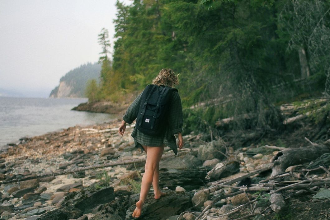 woman with backpack exploring rocky beach alone