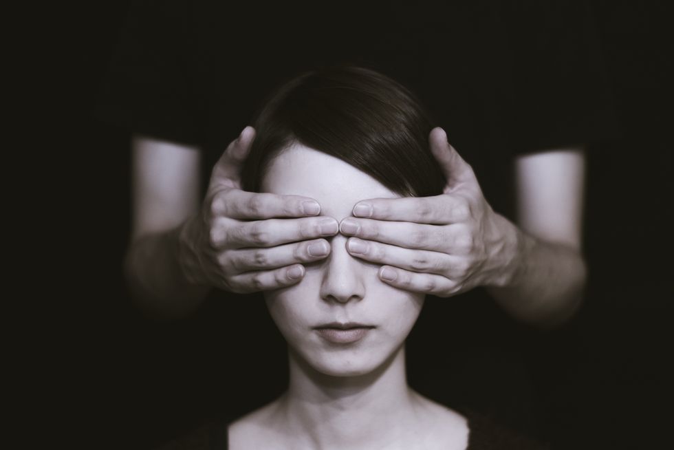Woman with her eyes being covered by someone else's hands.
