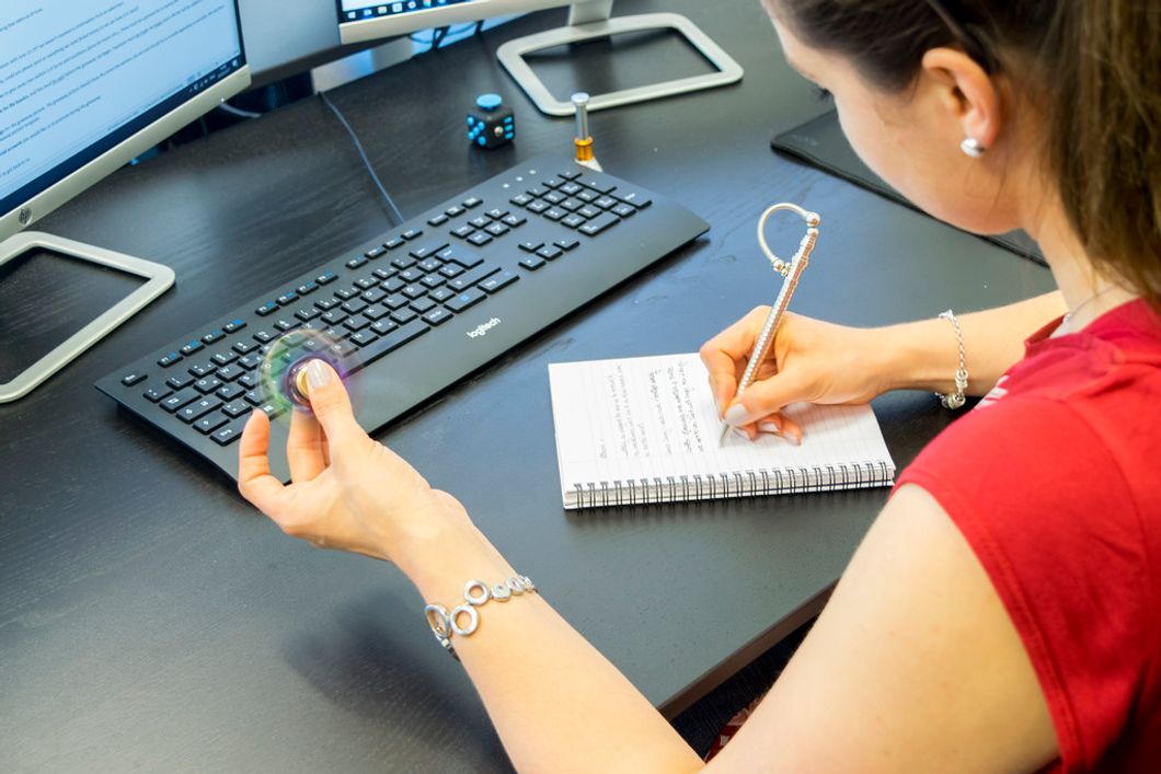 woman writing on deadline spinning fidget spinner