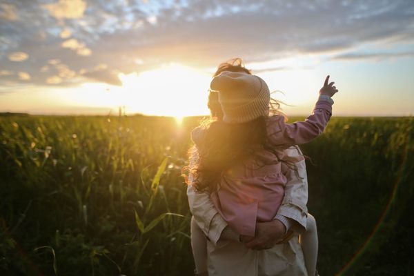 Women holding a small girl pointing up the sky