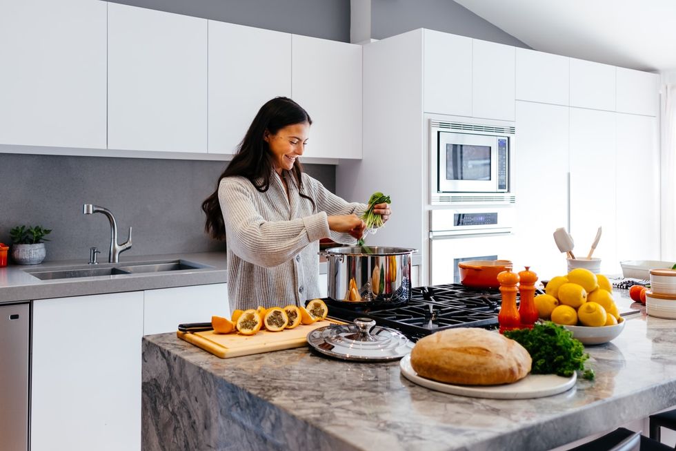 women smiling in kitchen mixing food in to a pot