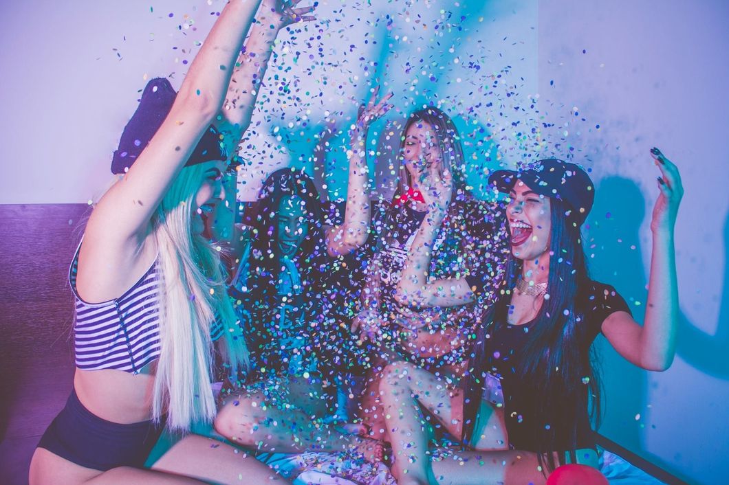 young women smiling throwing confetti in the air